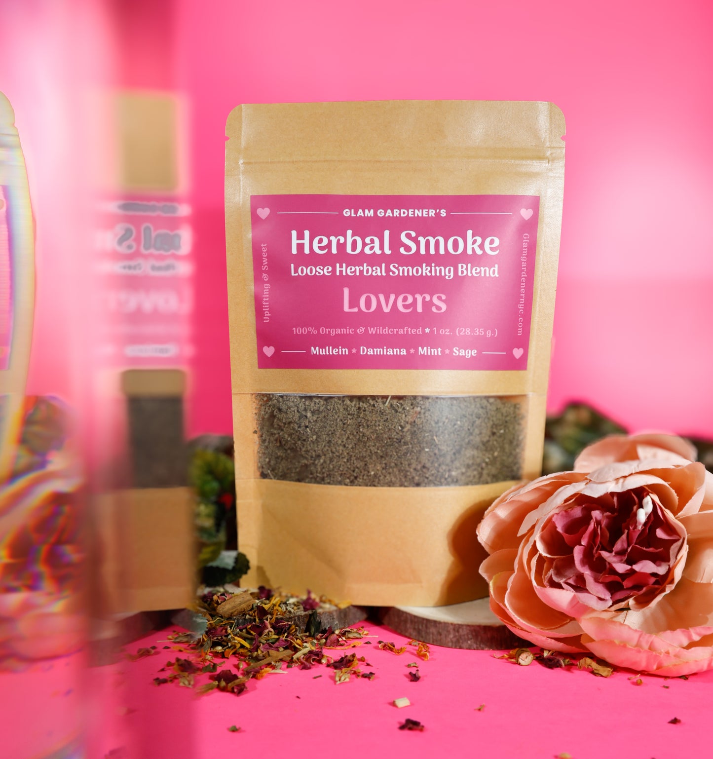 This image features, Glam Gardener NYC’s Lover’s herbal Smoking blended with Mullen, Damiana, mint, and sage. This photo features a pink background with a floral and botanical vibe to it. Glam Gardener NYC handcrafts herbal smoking blends and herbal teas.