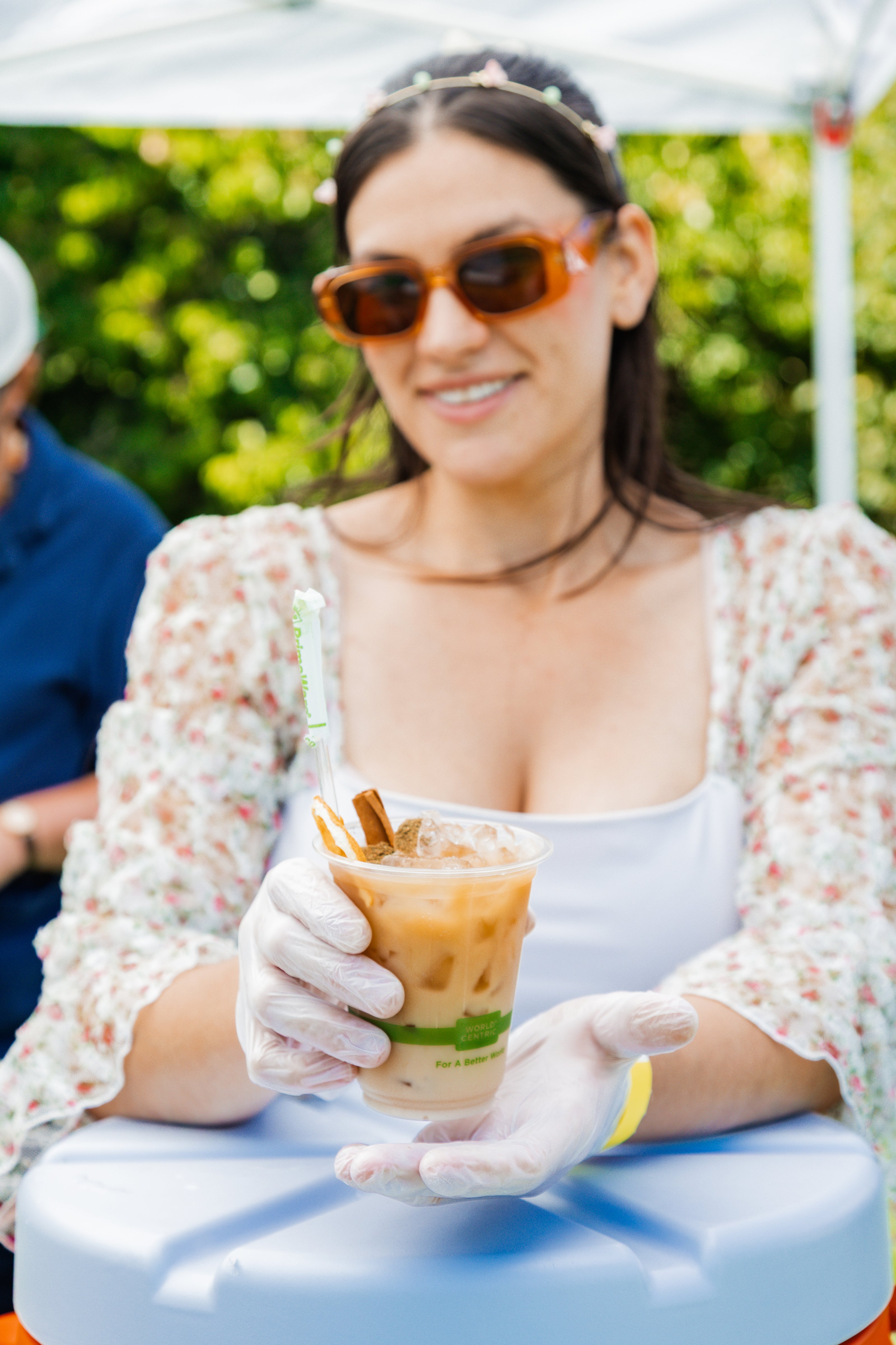 Glam Gardeners Herbal Mocktail Service in NYC! This is the 7 Mushroom Vanilla Chai Coffee, a signature beverage of Glam Gardener's Botanical Bar. This image shows the bartender, the Glam Gardener holding the beverage in a compostable cup.