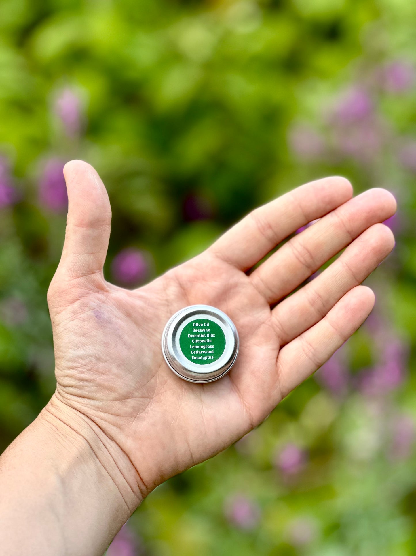 Hand holding small miniature bug repellent salve by Glam Gardener NYC. Clean and non-toxic ingredients include olive oil, American beeswax, citronella, Cedarwood, lemongrass and eucalyptus 