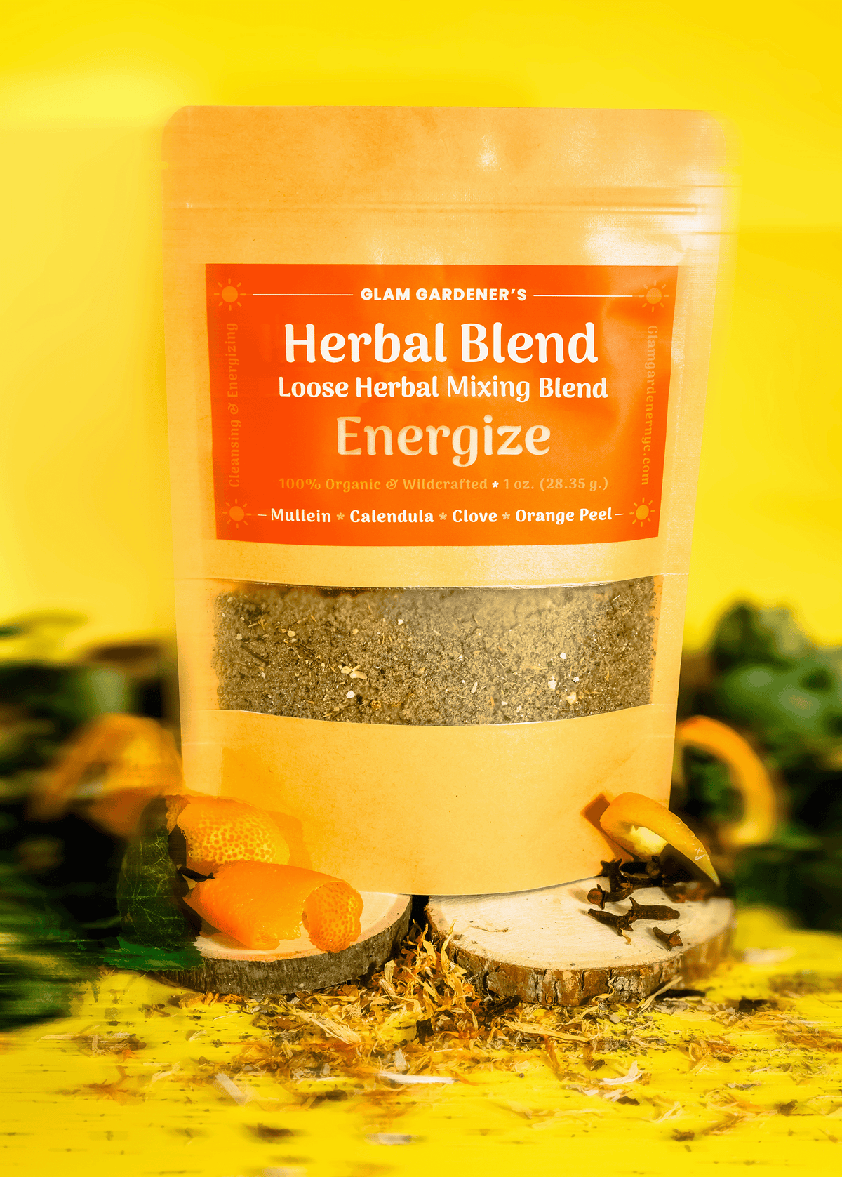 Glam Gardener's Pre-ground Herbal Mixing Blend with finely ground Mullein, Orange Peel, Calendula, and Clove. All ingredients are organic, wildcrafted, and pre-ground finely. The label is orange, the stand up pouch is brown and the background is yellow with green ivy, various colored plants.