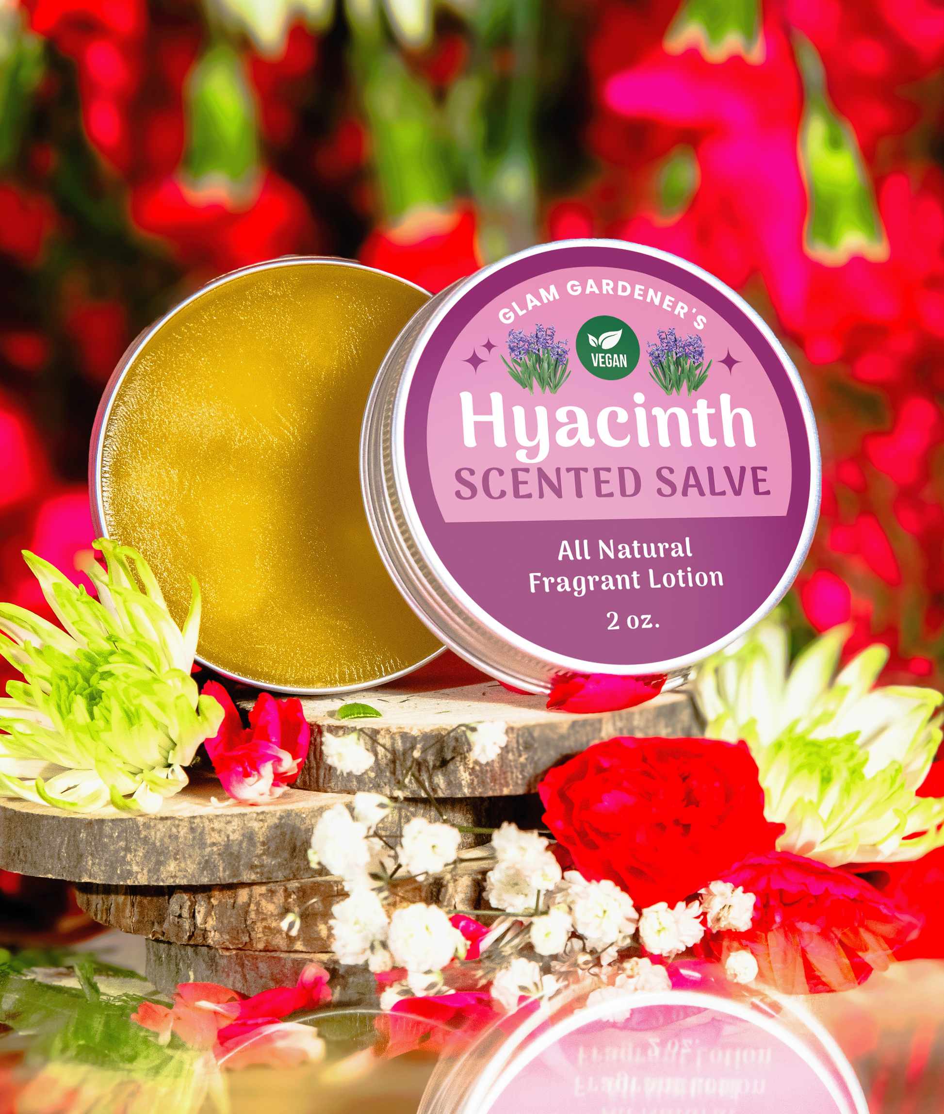 VEGAN HYACINTH BLOOMS • Natural solid perfume and hydrating lotion infused with Hyacinth absolute oil and plant-based wax. Backdrop features red background with flowers. The scented salve’s container is open showing the product’s contents.