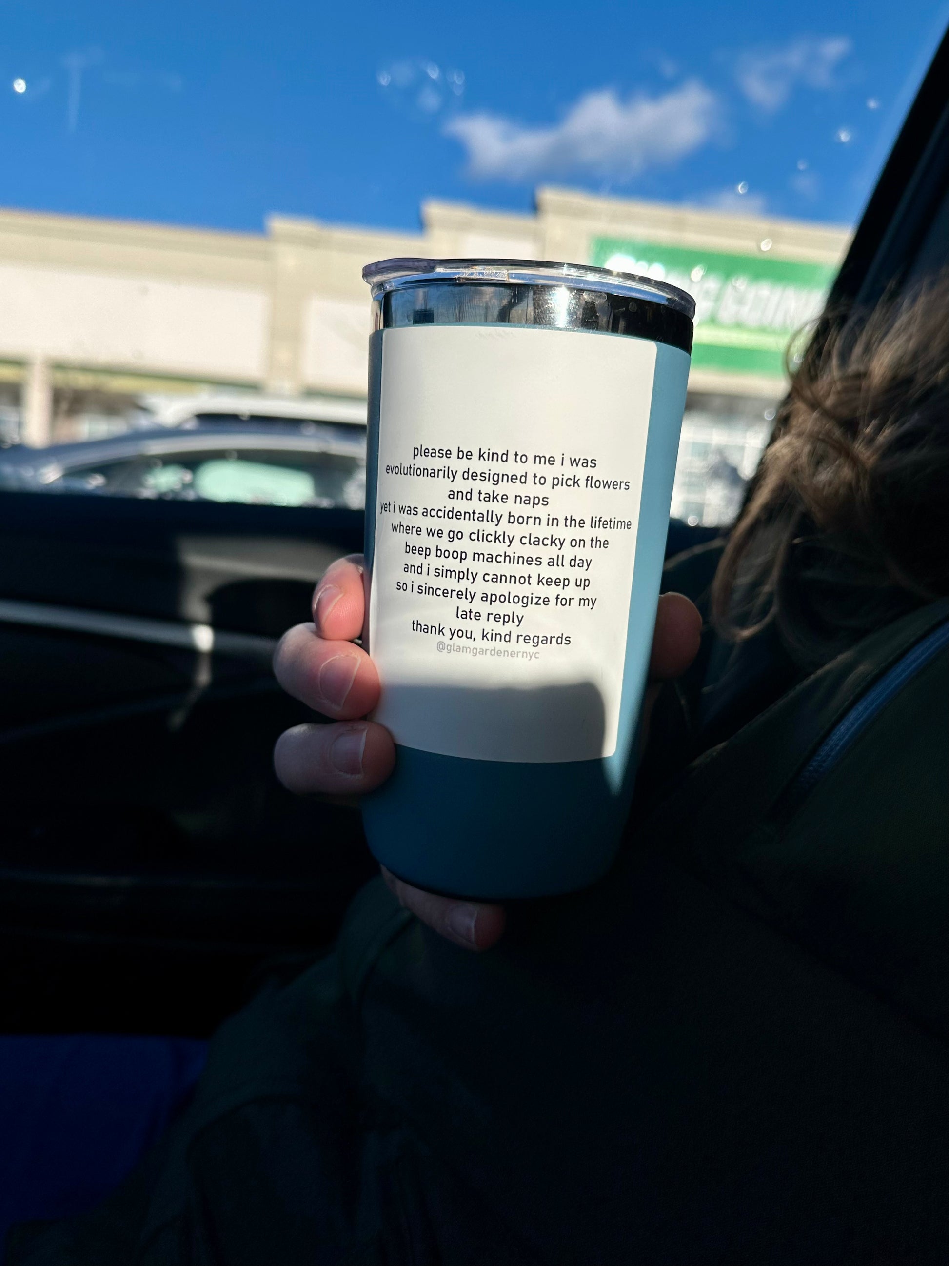 Man holding coffee cup with sticker on it that says, “ please be kind to me i was
evolutionarily designed to pick flowers and take naps
yeti was accidentally born in the lifetime where we go clickly clacky on the beep boop machines all day and i simply cannot keep up so i sincerely apologize for my late reply
thank you, kind regards @glamgardenernyc” The sticker design is on a blank white background designed to look like a sheet of paper or an email. 