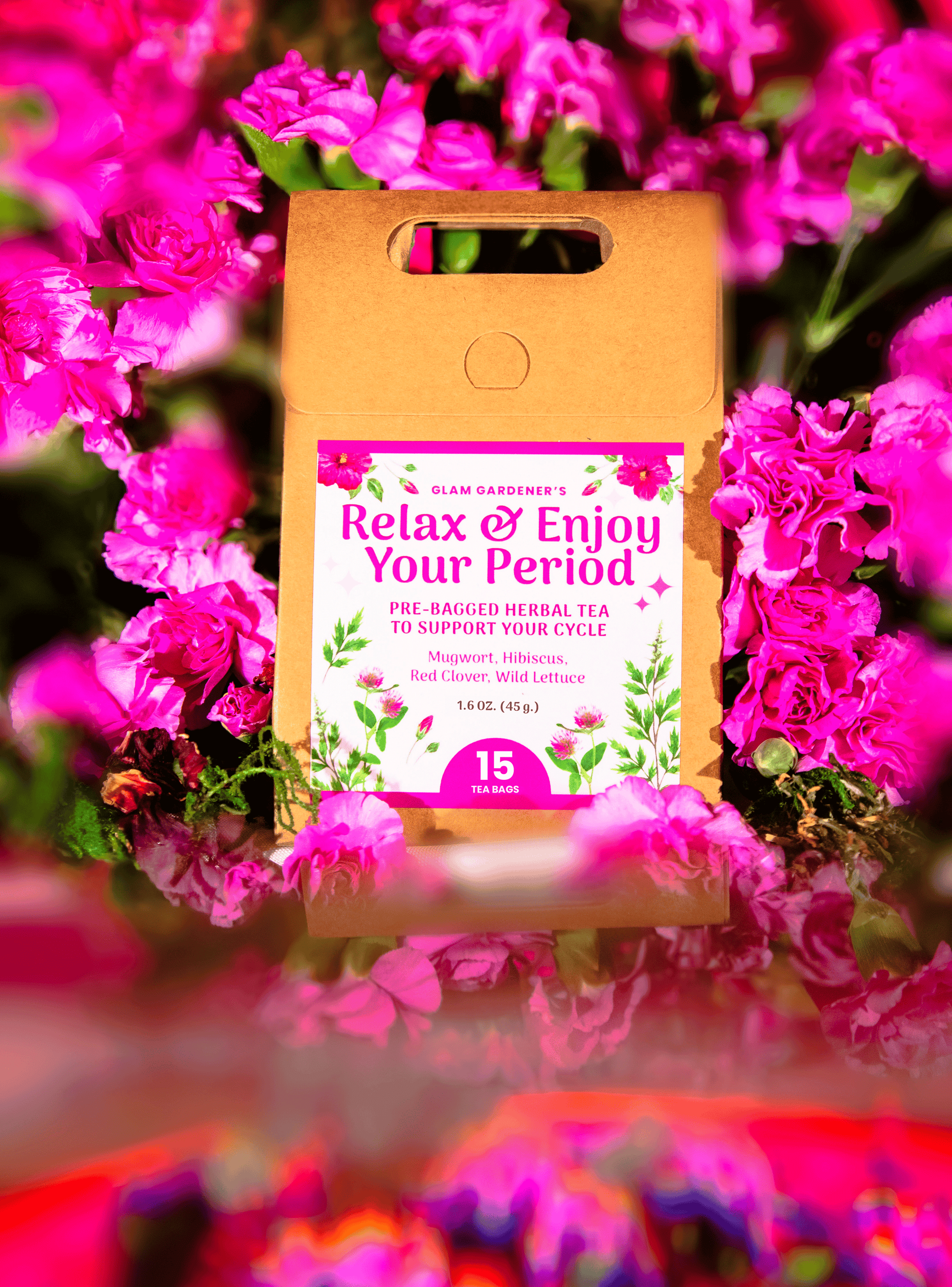 A kraft paper pouch of Slam Gardens 'Relax & Enjoy Your Period' herbal tea by Glam Gardener, surrounded by a dense background of bright pink flowers.