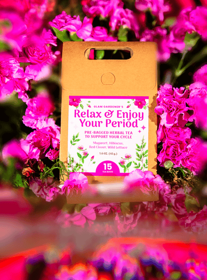 A kraft paper pouch of Slam Gardens 'Relax & Enjoy Your Period' herbal tea by Glam Gardener, surrounded by a dense background of bright pink flowers.