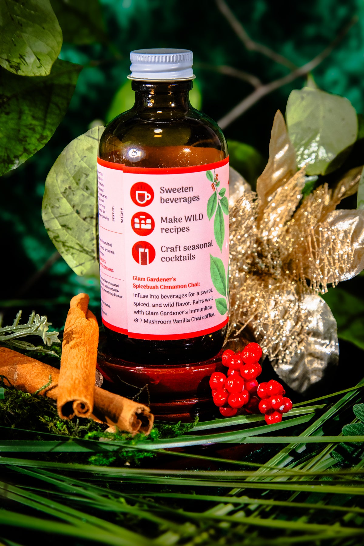 Glam Gardener's Spicebush Cinnamon Chai Simple Syrup with organic and wildcrafted ingredients. Cinnamon, Wild Spicebush (Lindera benzoin), Cardamom. Organic sugar and handcrafted. Red label and floral background. Hand harvested wild spicebush leaves. Simple syrup for fall and winter.