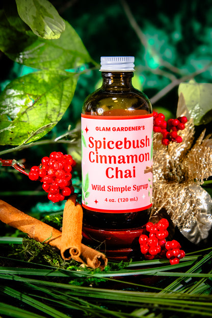 Glam Gardener's Spicebush Cinnamon Chai Simple Syrup with organic and wildcrafted ingredients. Cinnamon, Wild Spicebush (Lindera benzoin), Cardamom. Organic sugar and handcrafted. Red label and floral background. Hand harvested wild spicebush leaves. Simple syrup for fall and winter.